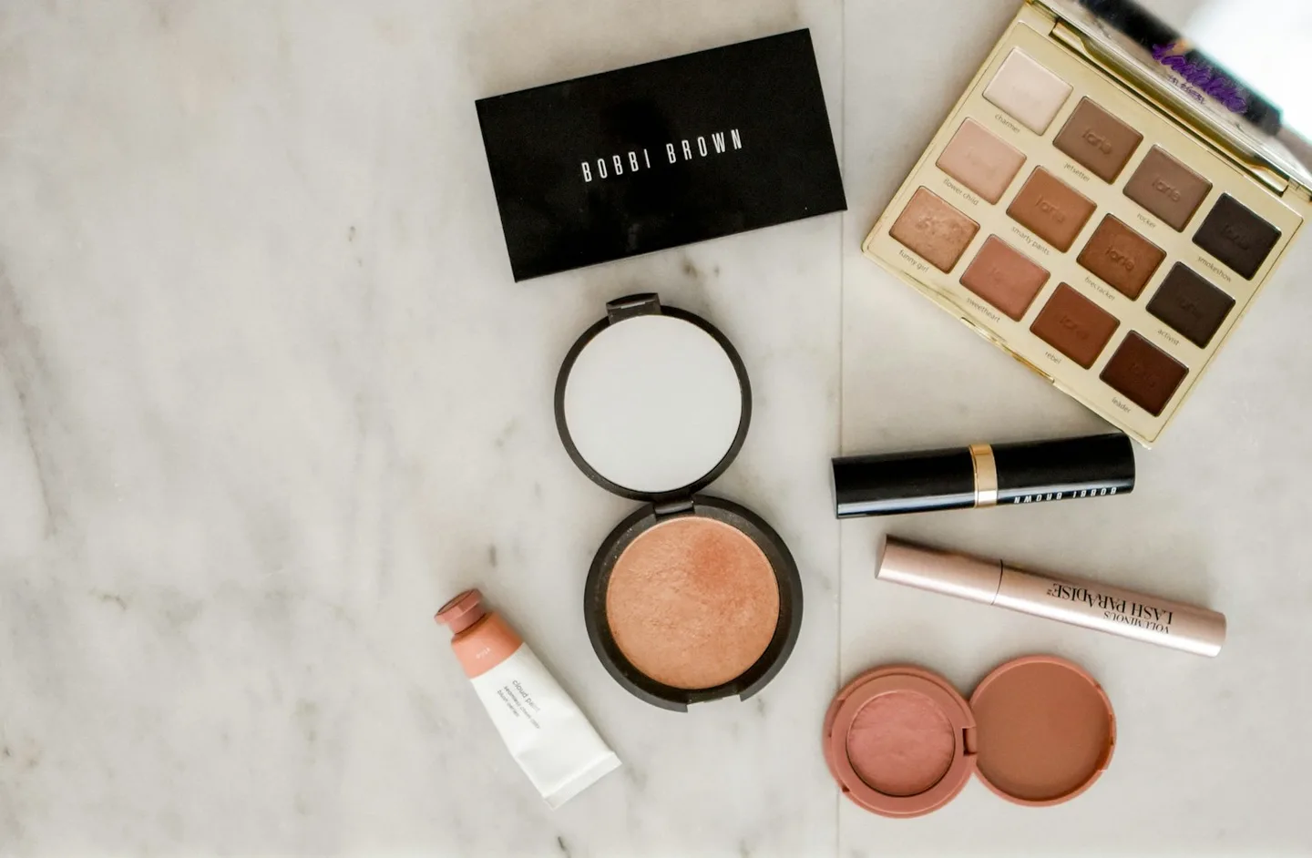 Makeup essentials on a pale tabletop