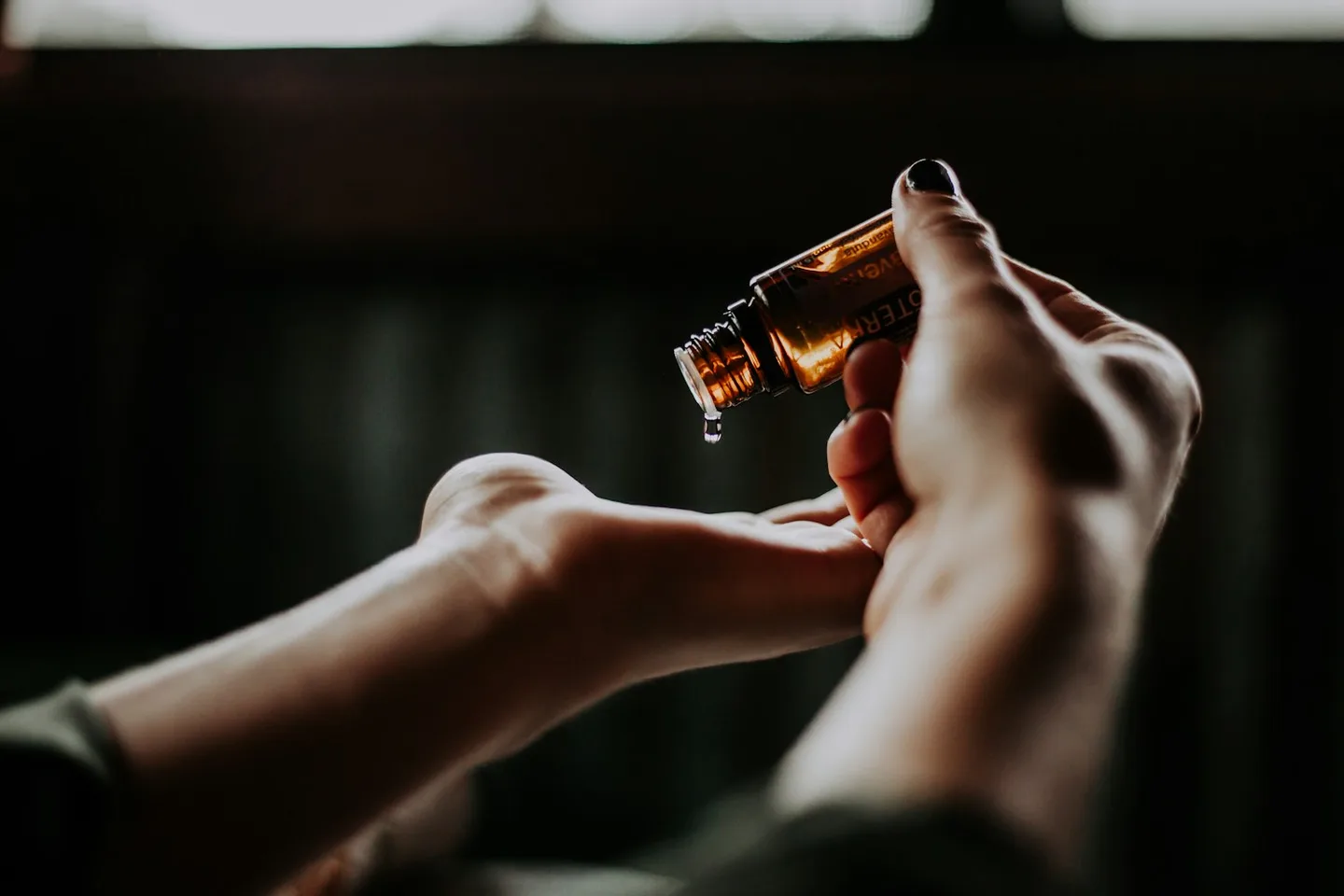 Cosmetic oil being dispensed into an open palm