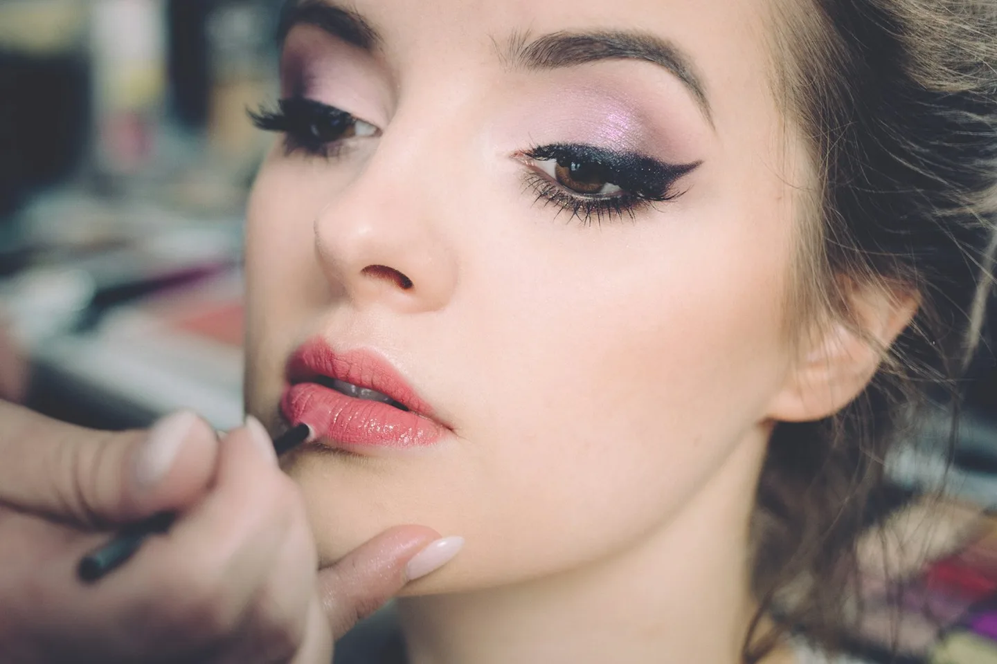 A makeup artist applying lip color to a woman