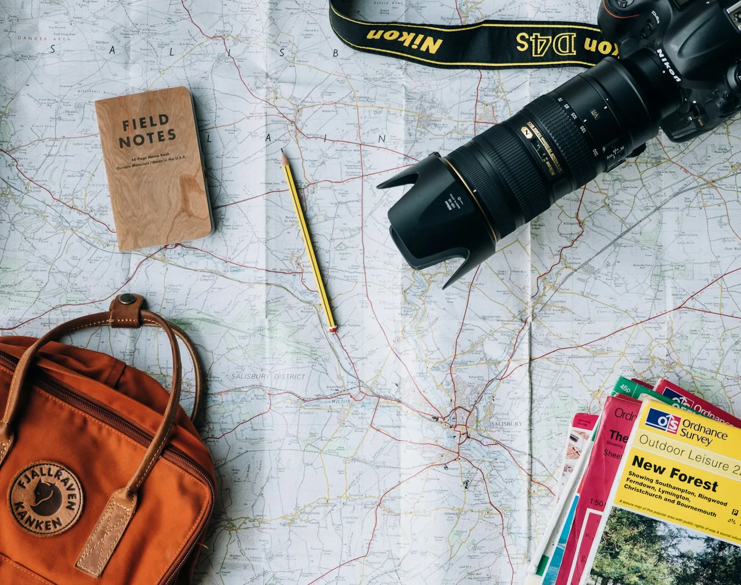 A map, camera, and travel bag arranged for a journey