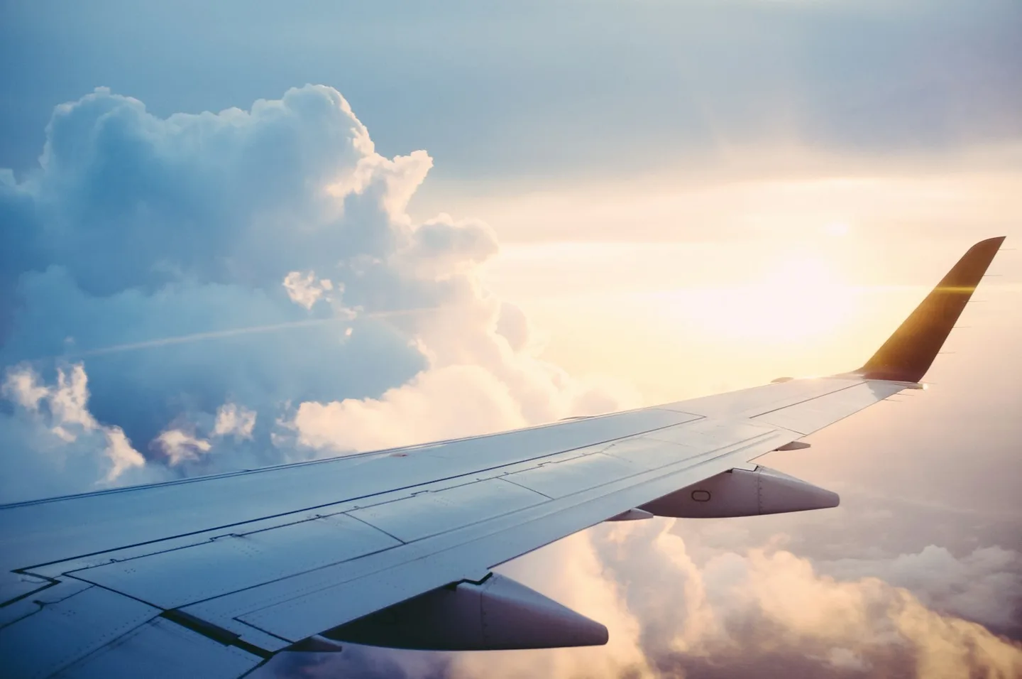 An airplane wing above clouds at sunset